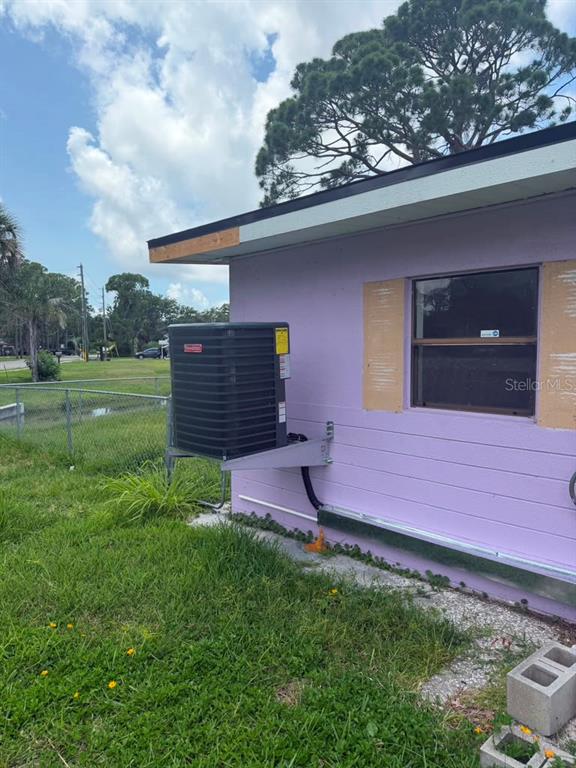 A wall-mounted HVAC condenser unit is attached to the exterior of a purple house — 7235 ROYAL PALM DRIVE, NEW PORT RICHEY, FL