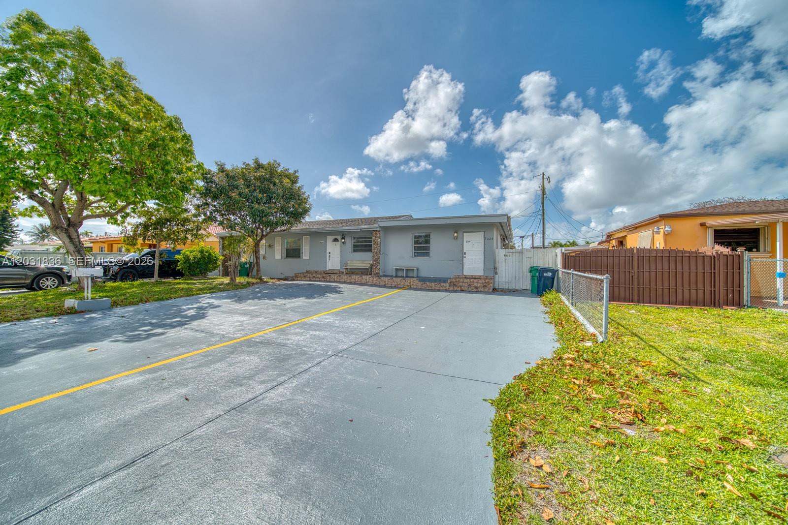 A gray single-story house features a large paved driveway with a yellow painted line — 7622 SW 21st St # 7622, Miami FL 33155, MIAMI, FL