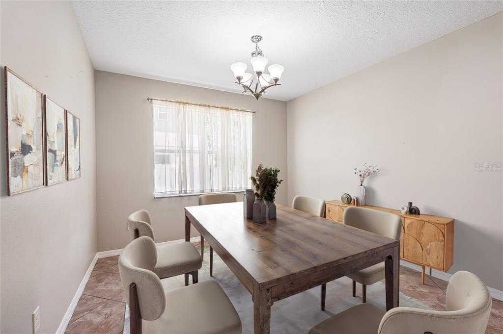 A dining room features a wooden table, six upholstered chairs, a chandelier, and a sideboard — 2426 CUMBERLAND CLIFF DRIVE, RUSKIN, FL