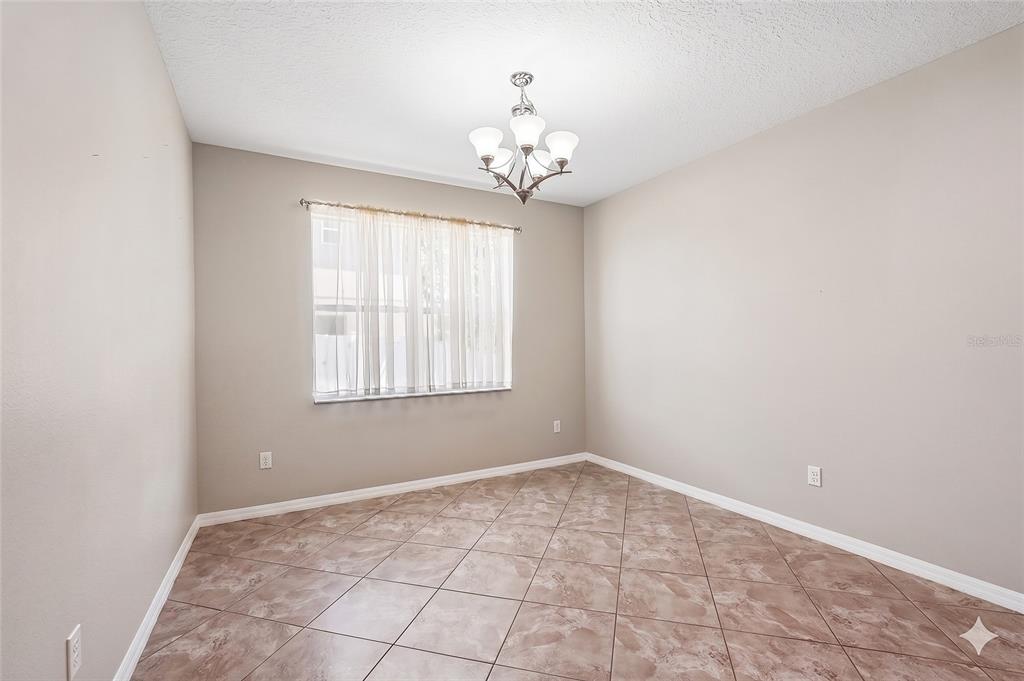 An empty dining room features beige walls, a tile floor, and a central chandelier — 2426 CUMBERLAND CLIFF DRIVE, RUSKIN, FL