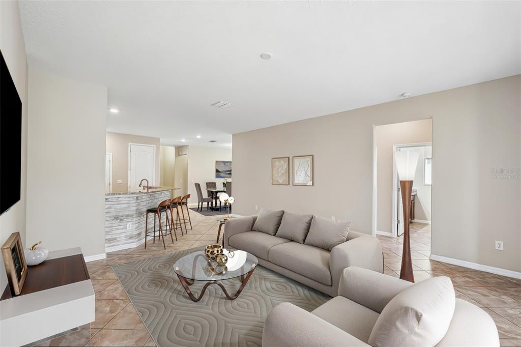 A living room with tile floors, a gray sofa, a glass coffee table, and a bar — 2426 CUMBERLAND CLIFF DRIVE, RUSKIN, FL
