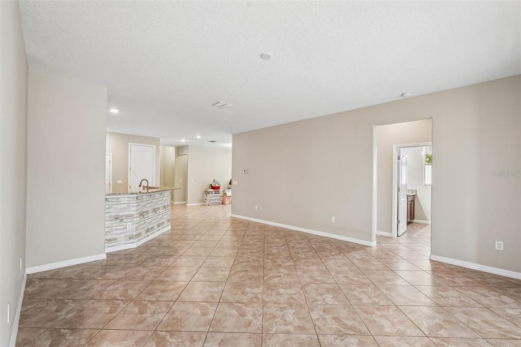 An open-concept living area features beige walls, tile flooring, and a kitchen breakfast bar — 2426 CUMBERLAND CLIFF DRIVE, RUSKIN, FL