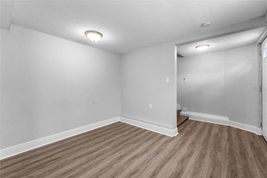 A room with light gray walls, wood-look flooring, and a doorway leading to stairs — 115 W ALLISON COURT, TAMPA, FL