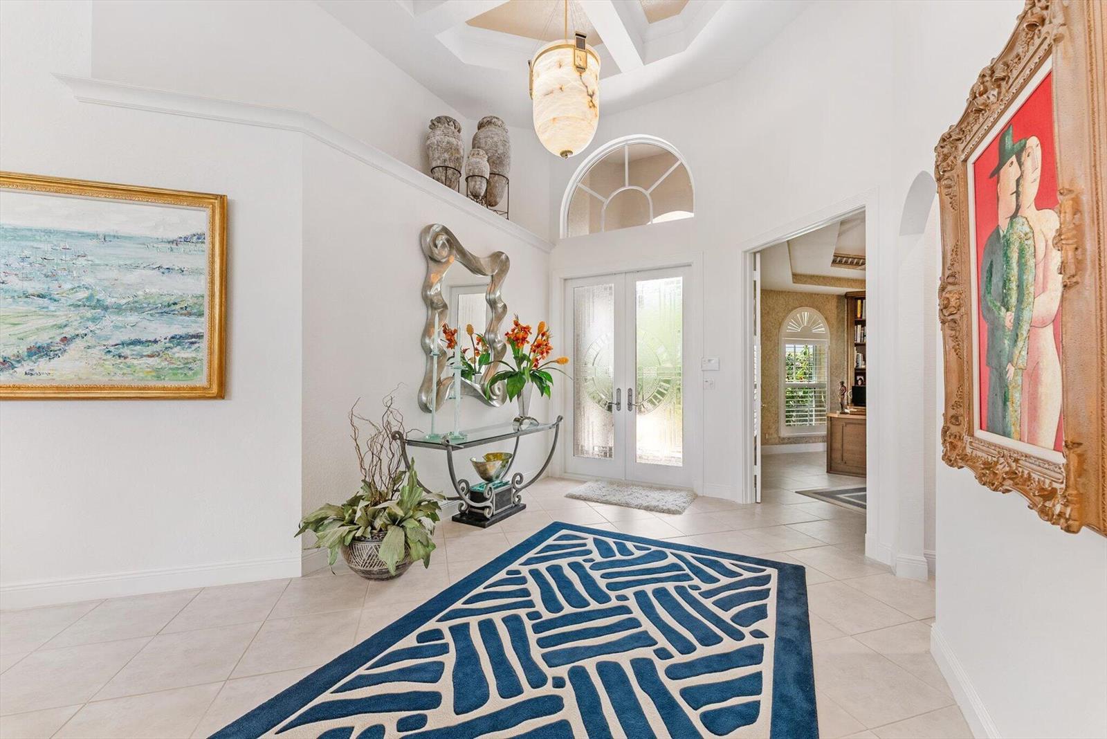 A bright foyer features a patterned blue rug, a glass console table, and two paintings — 6533 Somerset Circle, Boca Raton FL 33496, BOCA RATON, FL