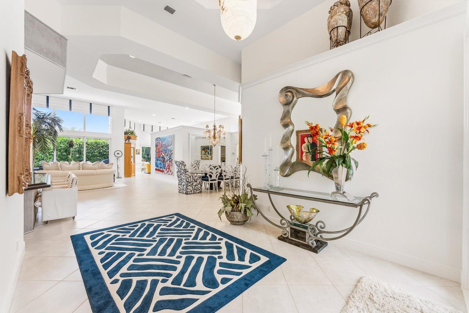 A spacious, tiled foyer features a blue patterned rug, a console table, and a mirror — 6533 Somerset Circle, Boca Raton FL 33496, BOCA RATON, FL