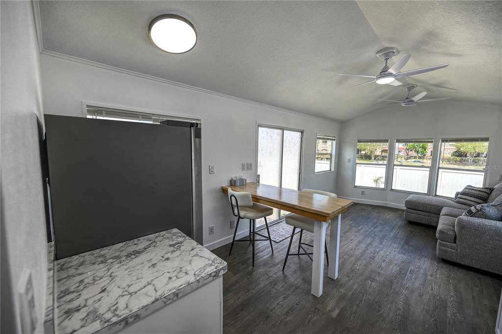 A kitchen and living area features a marble-patterned counter, a wooden breakfast bar, and flooring — 6720 PARK BOULEVARD N UNIT 1, PINELLAS PARK, FL