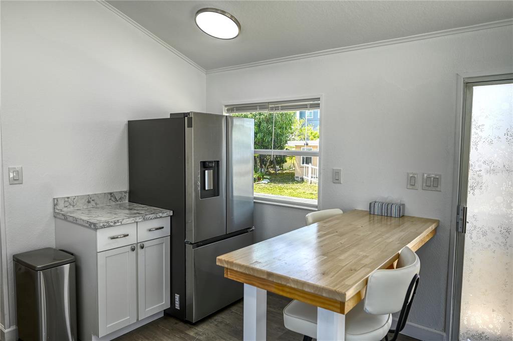 A kitchen area features a stainless steel refrigerator, white cabinets, and a wooden dining table — 6720 PARK BOULEVARD N UNIT 1, PINELLAS PARK, FL