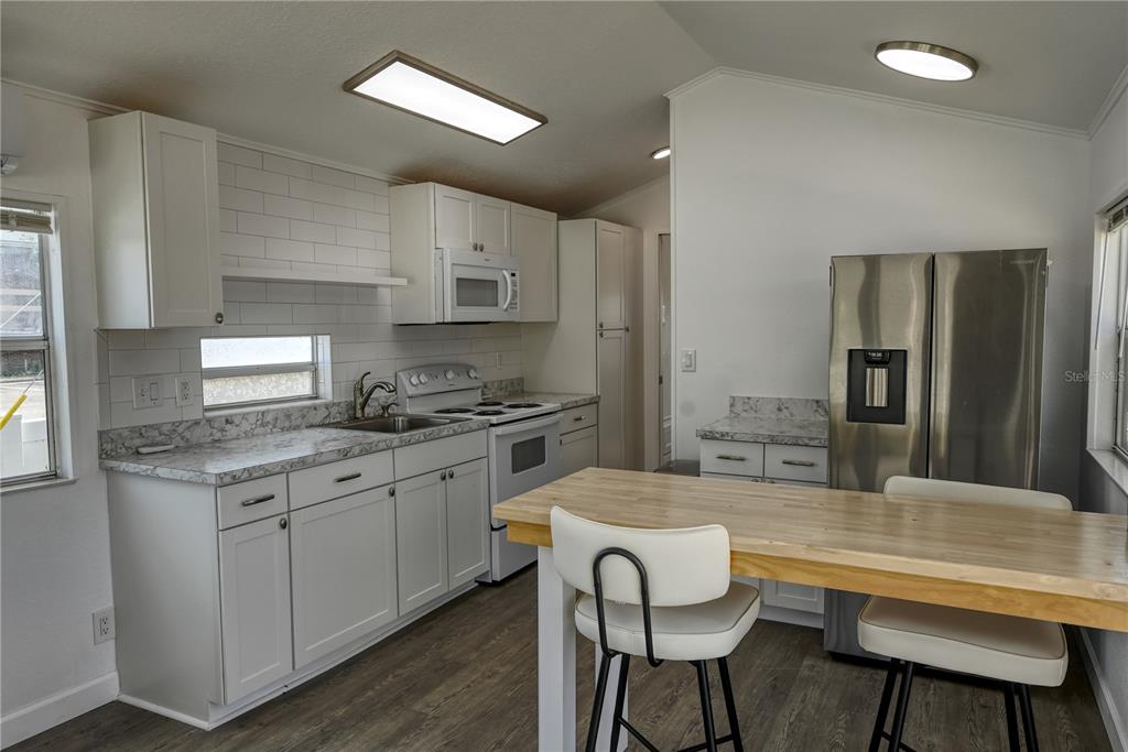 A kitchen features white cabinets, a butcher block island, stainless steel appliances, and subway tile — 6720 PARK BOULEVARD N UNIT 1, PINELLAS PARK, FL