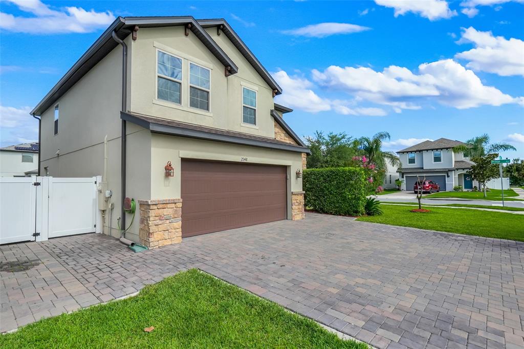 A two-story house with a brown garage door, stone accents, and a paved driveway — 2948 CREST DRIVE, KISSIMMEE, FL