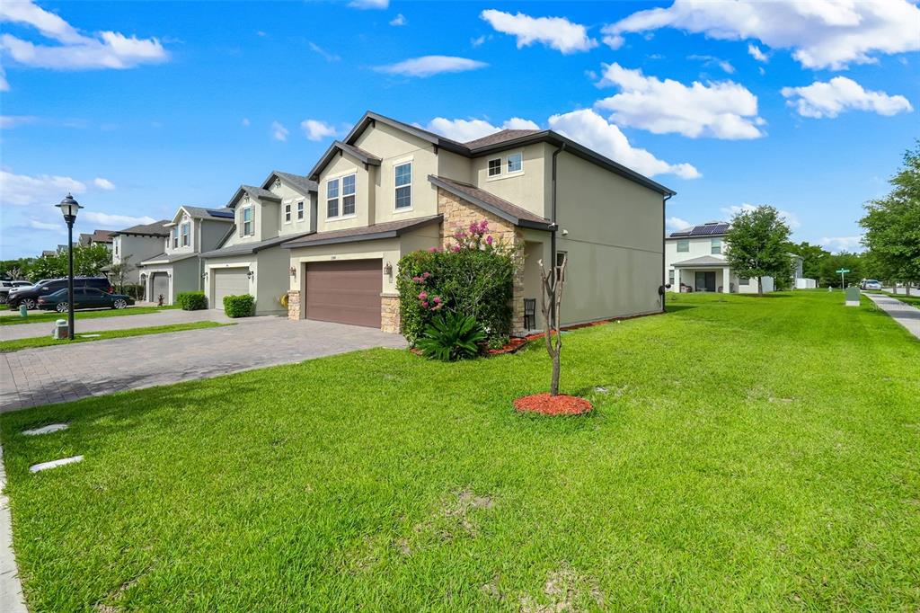 A two-story suburban townhouse with a tan stucco exterior, stone accents, and a paved driveway — 2948 CREST DRIVE, KISSIMMEE, FL