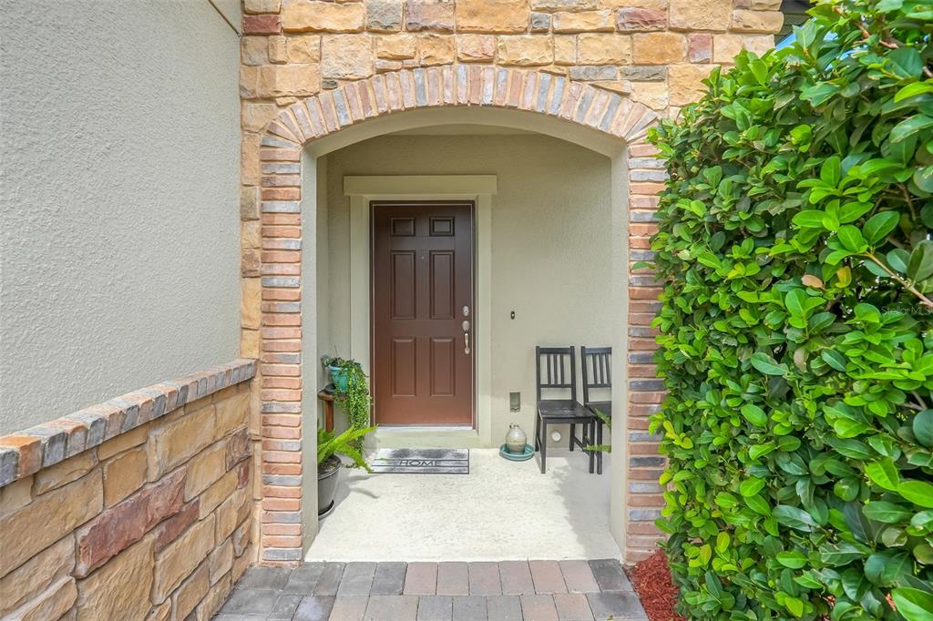 An arched entryway features a brown door, stone facade, and a small patio area — 2948 CREST DRIVE, KISSIMMEE, FL