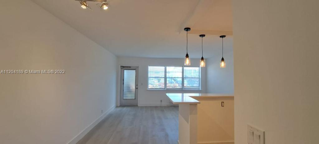 An interior view of a living area with light wood floors, a breakfast bar, and pendants — 155 Easthampton G # 155, West Palm Beach FL 33417, WEST PALM BEACH, FL
