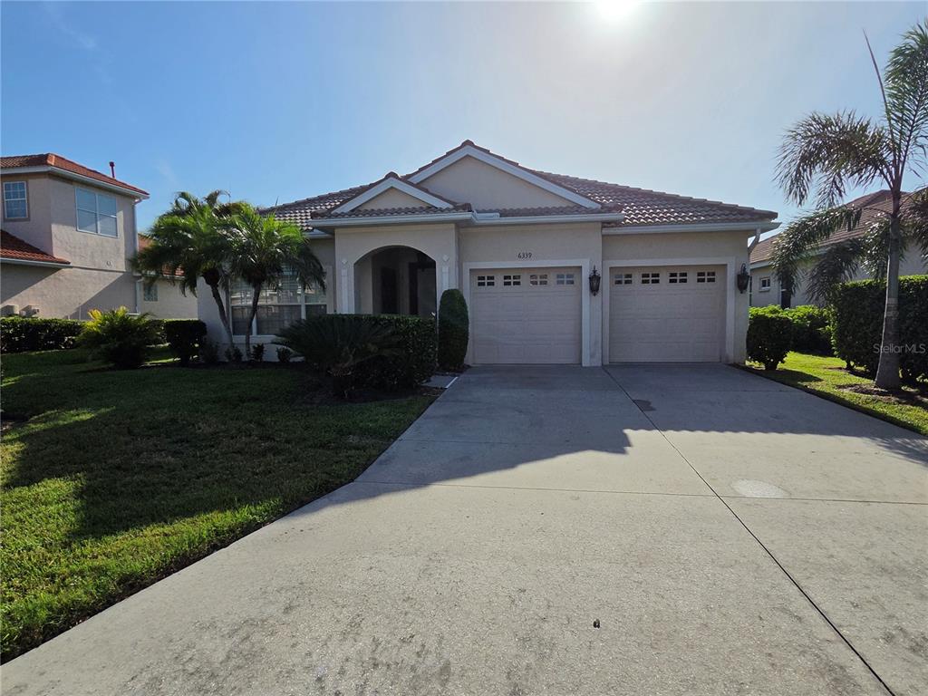 A single-story house with a two-car garage and a concrete driveway under a sunny sky — 6339 ROOKERY CIRCLE, BRADENTON, FL