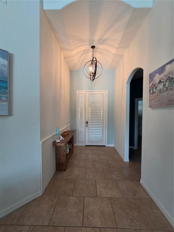A foyer with tiled floors, a vaulted ceiling, a pendant light, and a wooden console table — 6339 ROOKERY CIRCLE, BRADENTON, FL