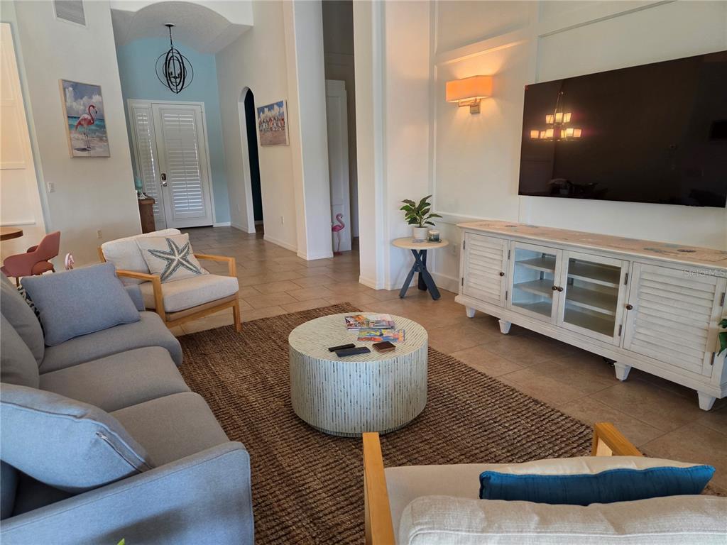 A living room features a grey sofa, two armchairs, a round coffee table, and a television — 6339 ROOKERY CIRCLE, BRADENTON, FL