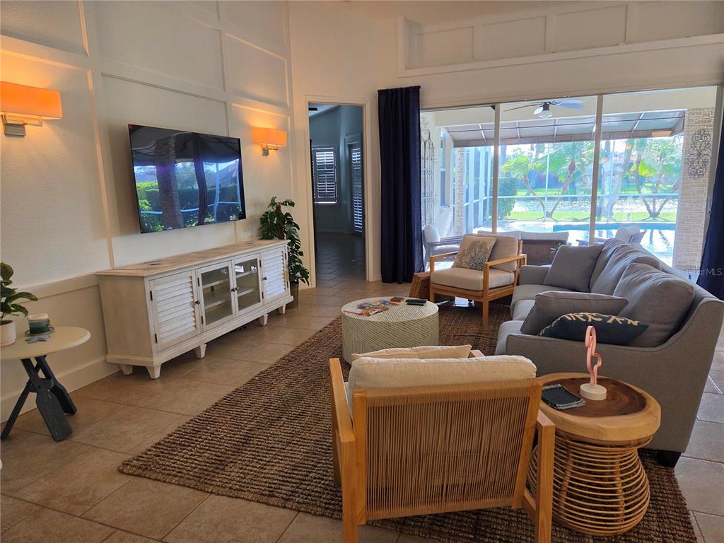A living room features a wall-mounted television, a white media console, and a large sliding door — 6339 ROOKERY CIRCLE, BRADENTON, FL