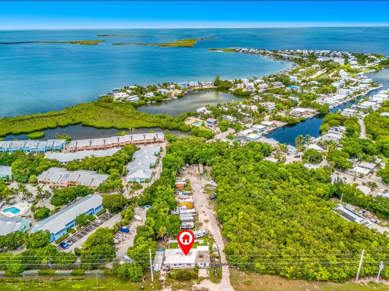 An aerial view shows a single-story house surrounded by dense trees near a coastal waterway — 98468 Overseas Hwy, Key Largo FL 33037, KEY LARGO, FL