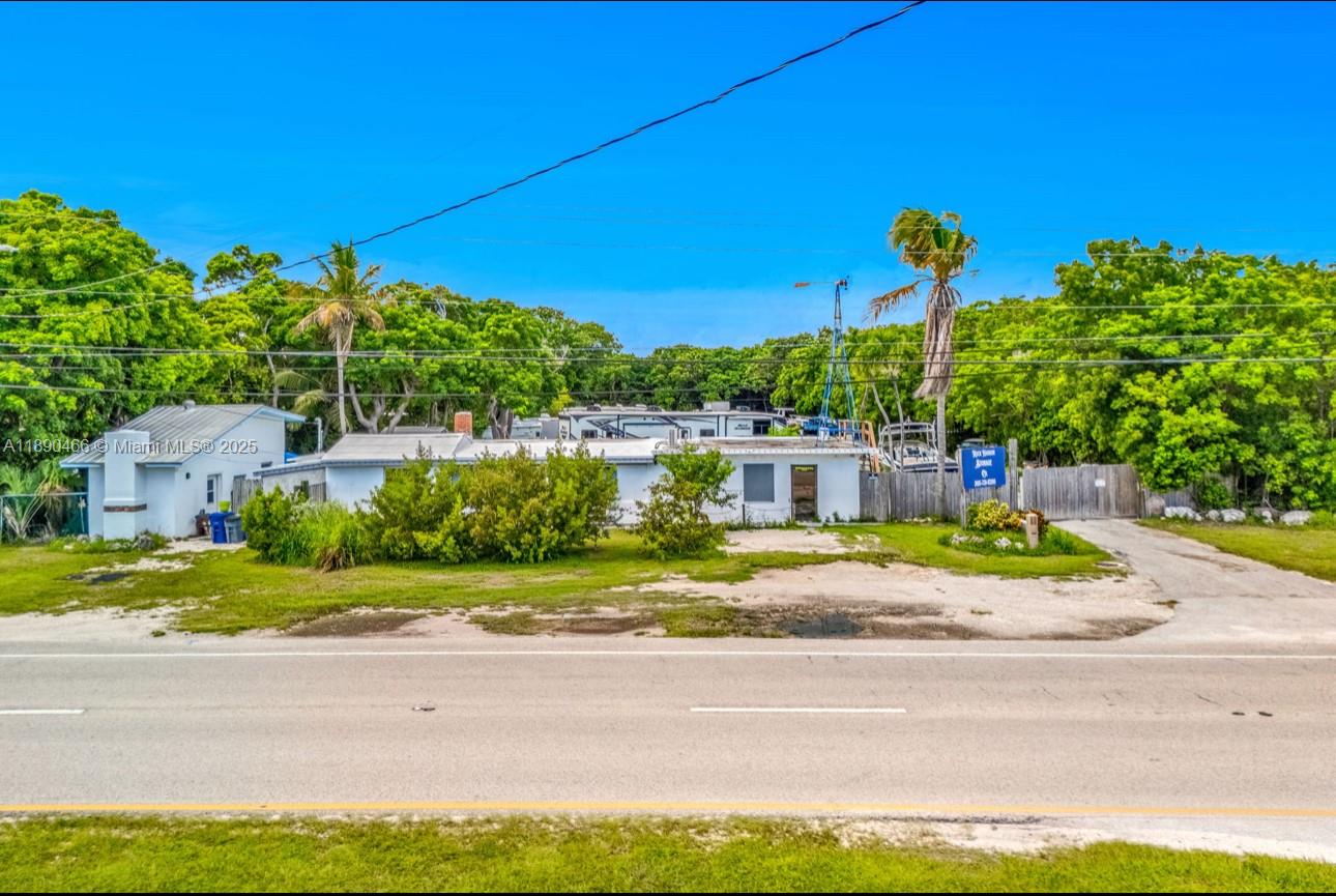 A single-story building with a flat roof sits behind a grassy yard and trees — 98468 Overseas Hwy, Key Largo FL 33037, KEY LARGO, FL