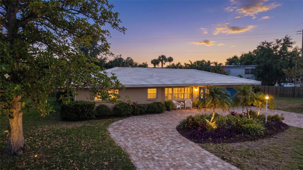 A single-story house with a white roof, tan stucco exterior, and a paved driveway at dusk — 3537 S SCHOOL AVENUE, SARASOTA, FL