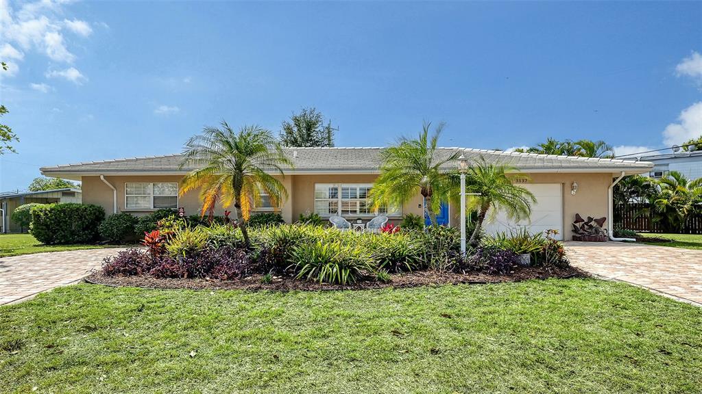 A single-story house with a beige exterior, a paved driveway, and palm trees in front — 3537 S SCHOOL AVENUE, SARASOTA, FL