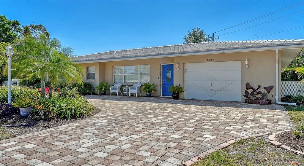 A single-story house with a paved driveway, blue front door, and a two-car garage — 3537 S SCHOOL AVENUE, SARASOTA, FL