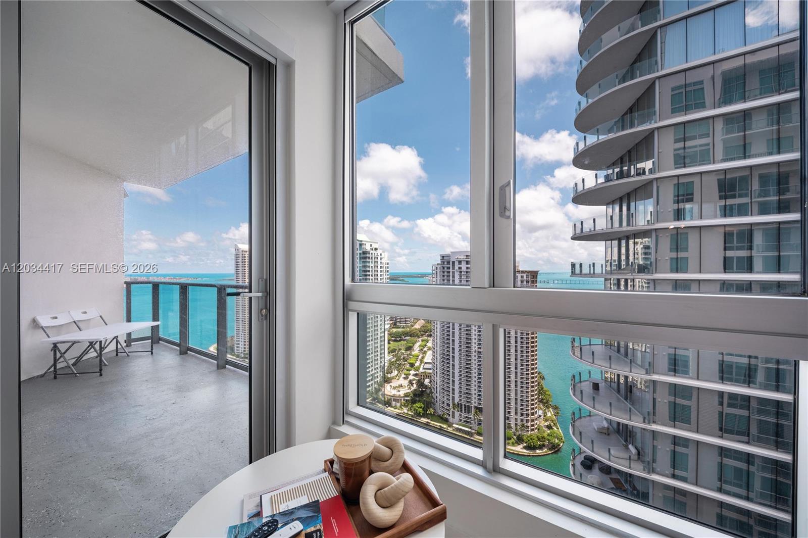 A room with a balcony and large windows overlooking a bay and high-rise buildings — 300 S Biscayne Blvd # 3406, Miami FL 33131, MIAMI, FL