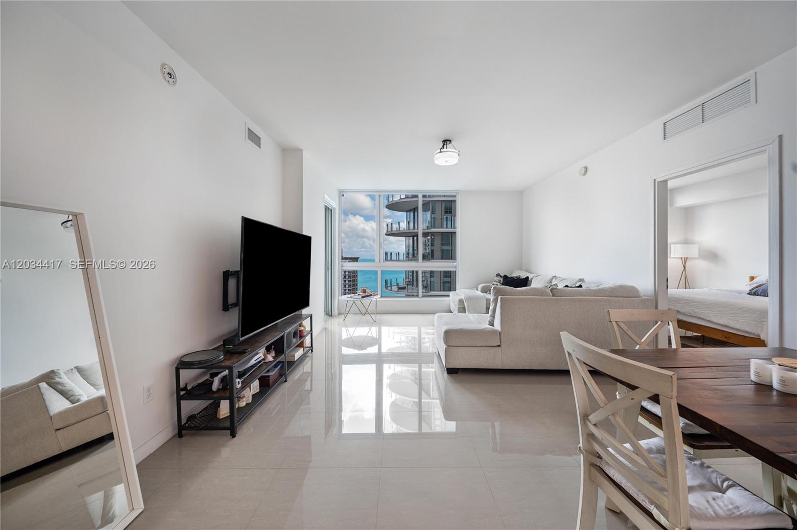 A living room with white tile floors, a sectional sofa, and a view of the ocean — 300 S Biscayne Blvd # 3406, Miami FL 33131, MIAMI, FL