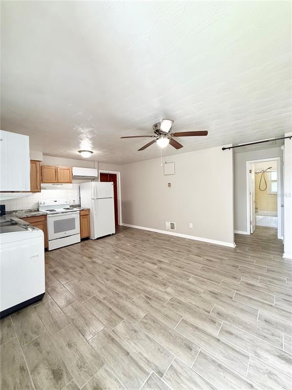 A kitchen and living area with wood-look tile flooring, white appliances, and a ceiling fan — 38839 3RD AVENUE, ZEPHYRHILLS, FL