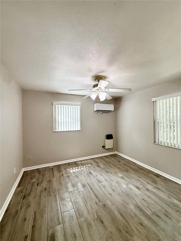 An empty bedroom features light-colored walls, wood-look tile flooring, a ceiling fan, and two windows — 38839 3RD AVENUE, ZEPHYRHILLS, FL