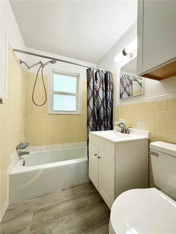 A bathroom features a white vanity, a toilet, and a bathtub with yellow wall tiles — 38839 3RD AVENUE, ZEPHYRHILLS, FL