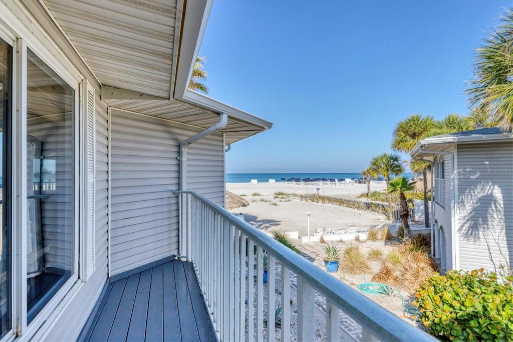 A balcony with a white railing overlooks a sandy beach and the ocean — 1336 BENJAMIN FRANKLIN DRIVE UNIT F2, SARASOTA, FL