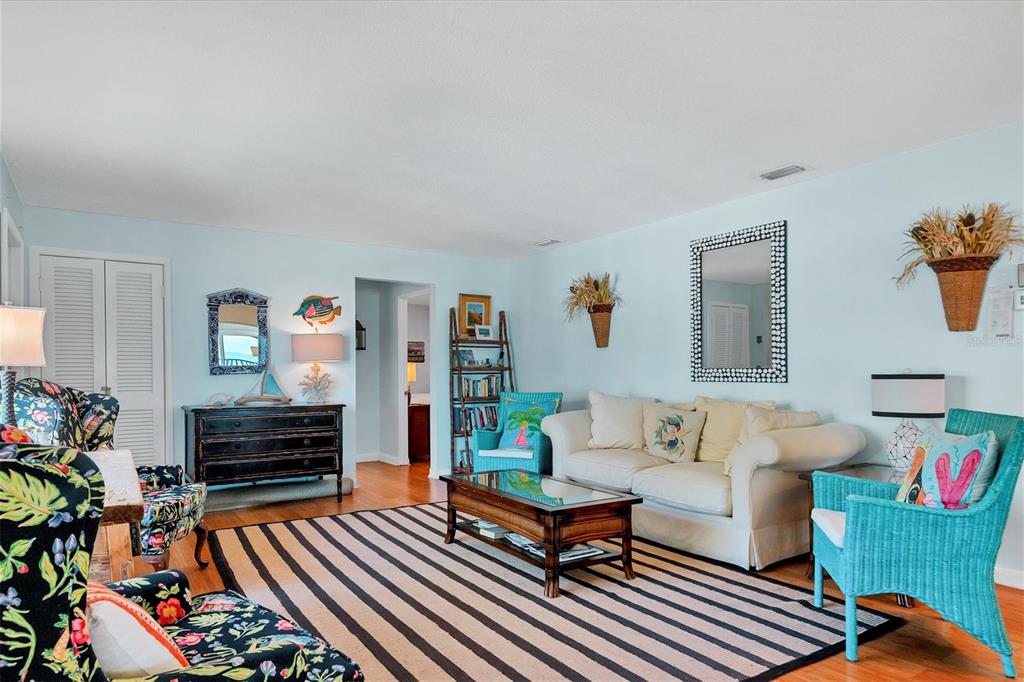 A living room features a striped rug, a white sofa, and colorful patterned armchairs — 1336 BENJAMIN FRANKLIN DRIVE UNIT F2, SARASOTA, FL