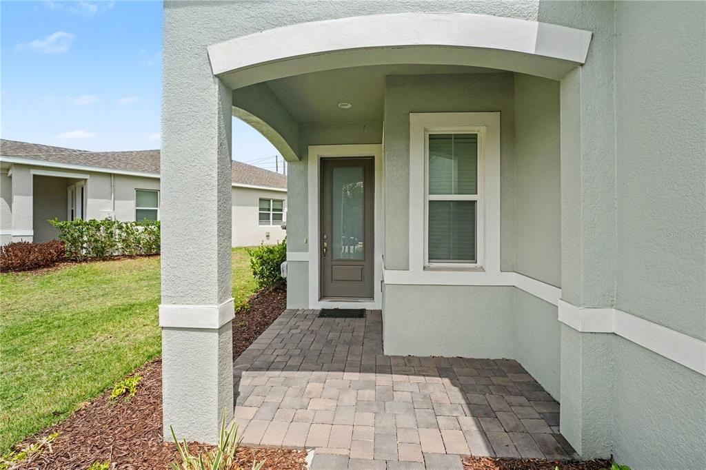 A covered entryway features a paver floor, a gray front door, and a single window — 1991 KEY BAY TRAIL, KISSIMMEE, FL