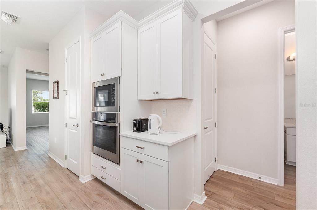 A kitchen area features white cabinets, a built-in oven and microwave, and light wood flooring — 1991 KEY BAY TRAIL, KISSIMMEE, FL