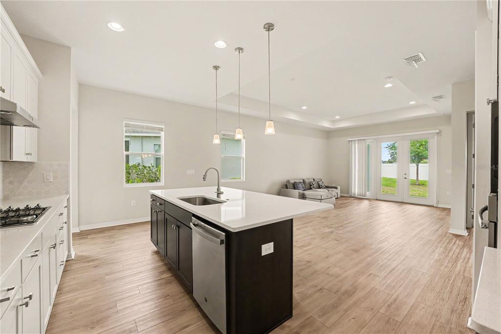 A kitchen with a dark island and white cabinets opens into a living area with doors — 1991 KEY BAY TRAIL, KISSIMMEE, FL