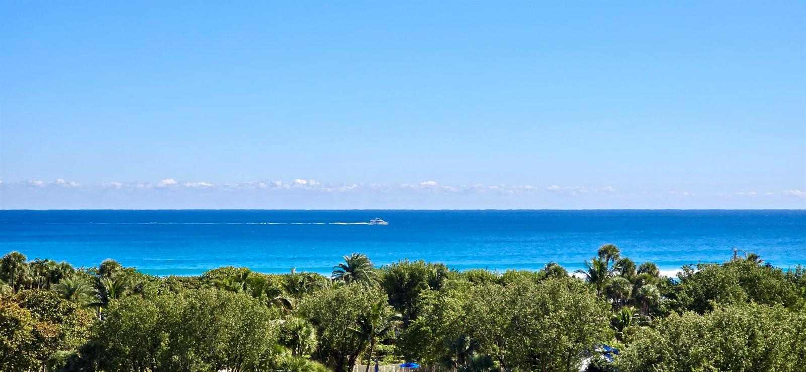 A view of the ocean and a boat from behind a line of trees — 4101 N Ocean Boulevard # 703, Boca Raton FL 33431, BOCA RATON, FL
