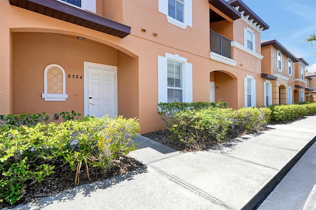 An exterior view of a multi-story apartment building with peach-colored stucco and white trim — 2724 COUPE STREET, KISSIMMEE, FL