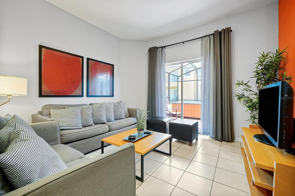 A living room features a gray sofa, a wooden coffee table, and a sliding glass door — 2724 COUPE STREET, KISSIMMEE, FL