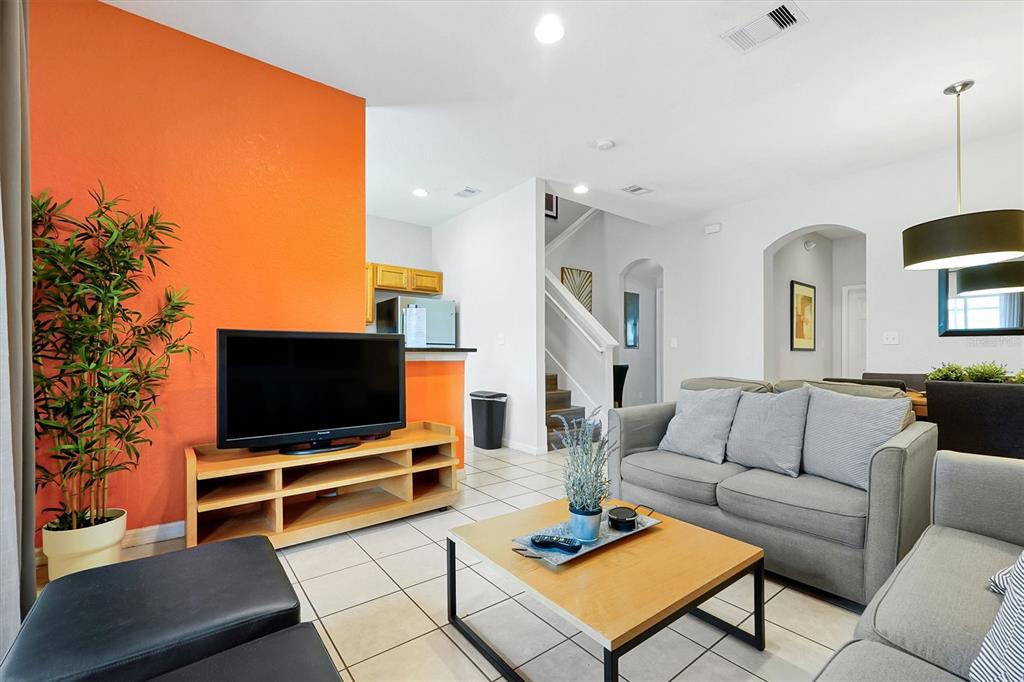 A living room features an orange accent wall, a grey sofa, and a wooden coffee table — 2724 COUPE STREET, KISSIMMEE, FL