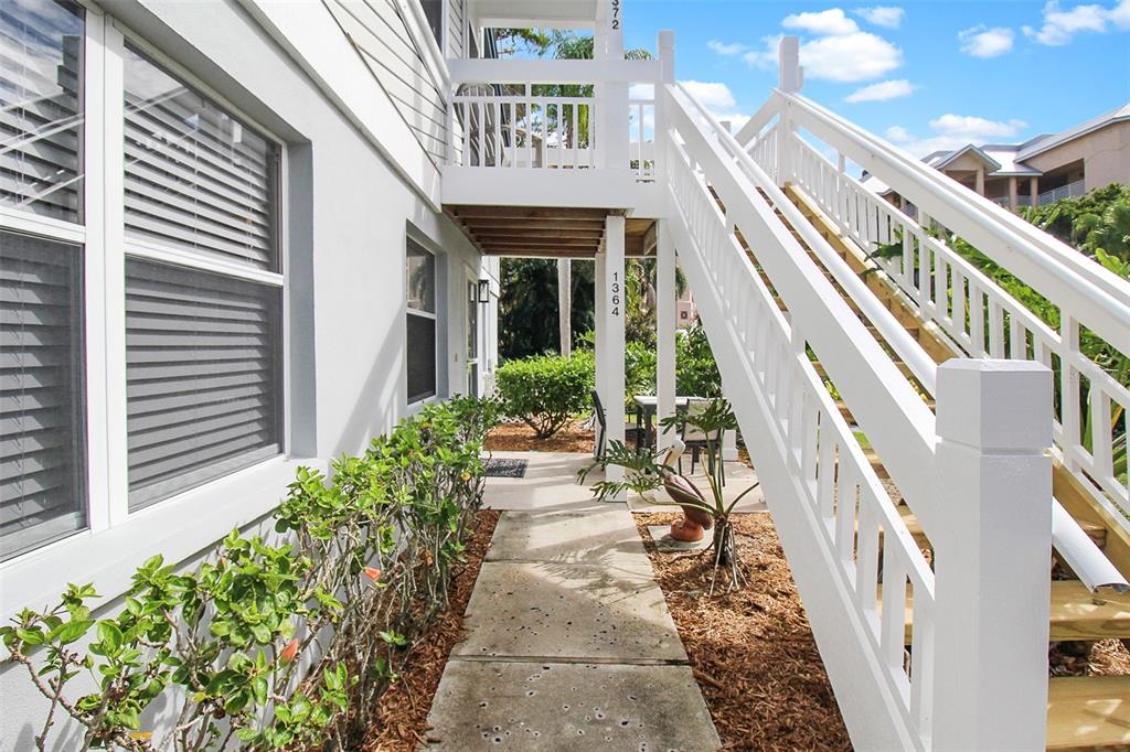A concrete walkway leads under an elevated wooden staircase beside a white building — 1364 SIESTA BAYSIDE DRIVE UNIT 1364-C, SARASOTA, FL