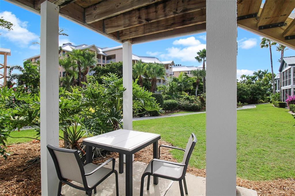 A patio with a small table and two chairs overlooks a grassy courtyard and buildings — 1364 SIESTA BAYSIDE DRIVE UNIT 1364-C, SARASOTA, FL