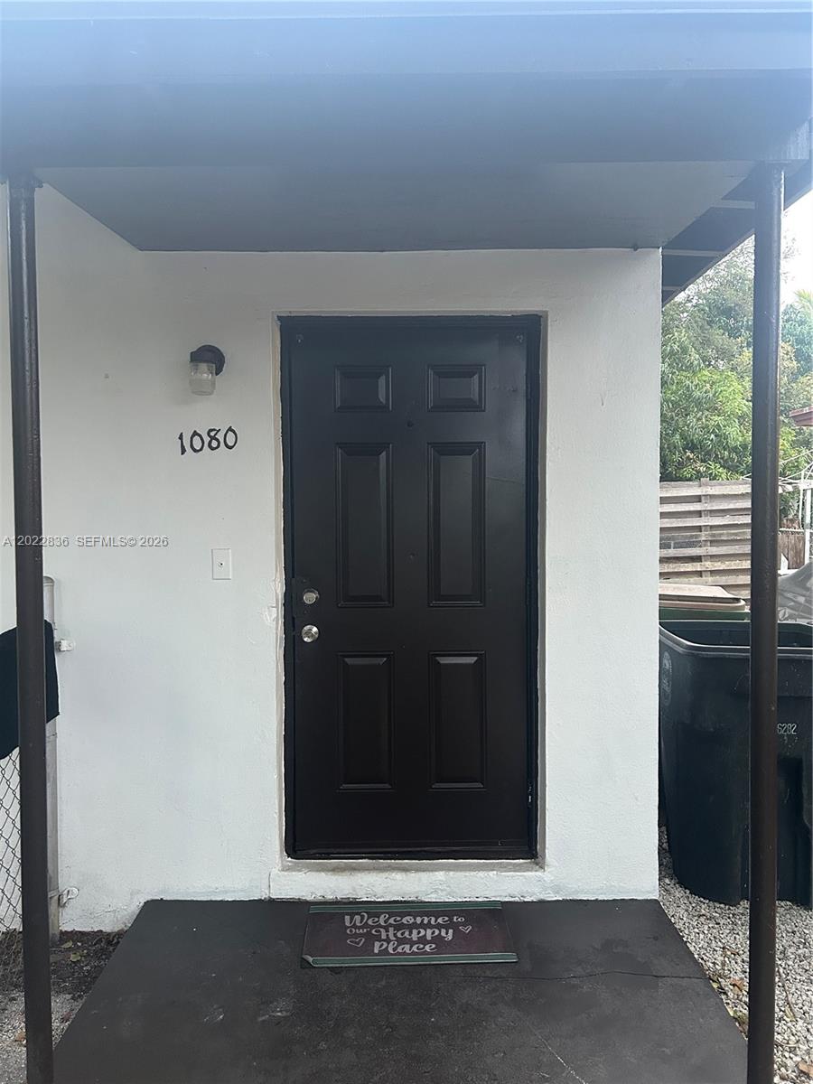 A black front door with the number 1080 on the white exterior wall — 1080 NW 121st St, North Miami FL 33168, NORTH MIAMI, FL