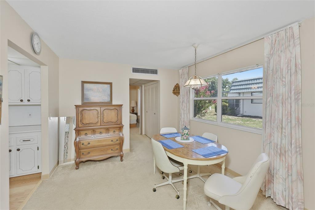 A dining area features a wooden table with four chairs, a dresser, and a window — 1811 BEDFORD LANE UNIT 163, SUN CITY CENTER, FL