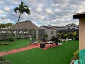 A backyard features artificial turf, a storage shed, patio furniture, and a tall palm tree — 11882 SW 209th Ter, Miami FL 33177, MIAMI, FL