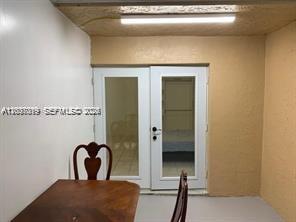 A dining area features a wooden table, chairs, and glass-paned double doors leading inside — 11882 SW 209th Ter, Miami FL 33177, MIAMI, FL