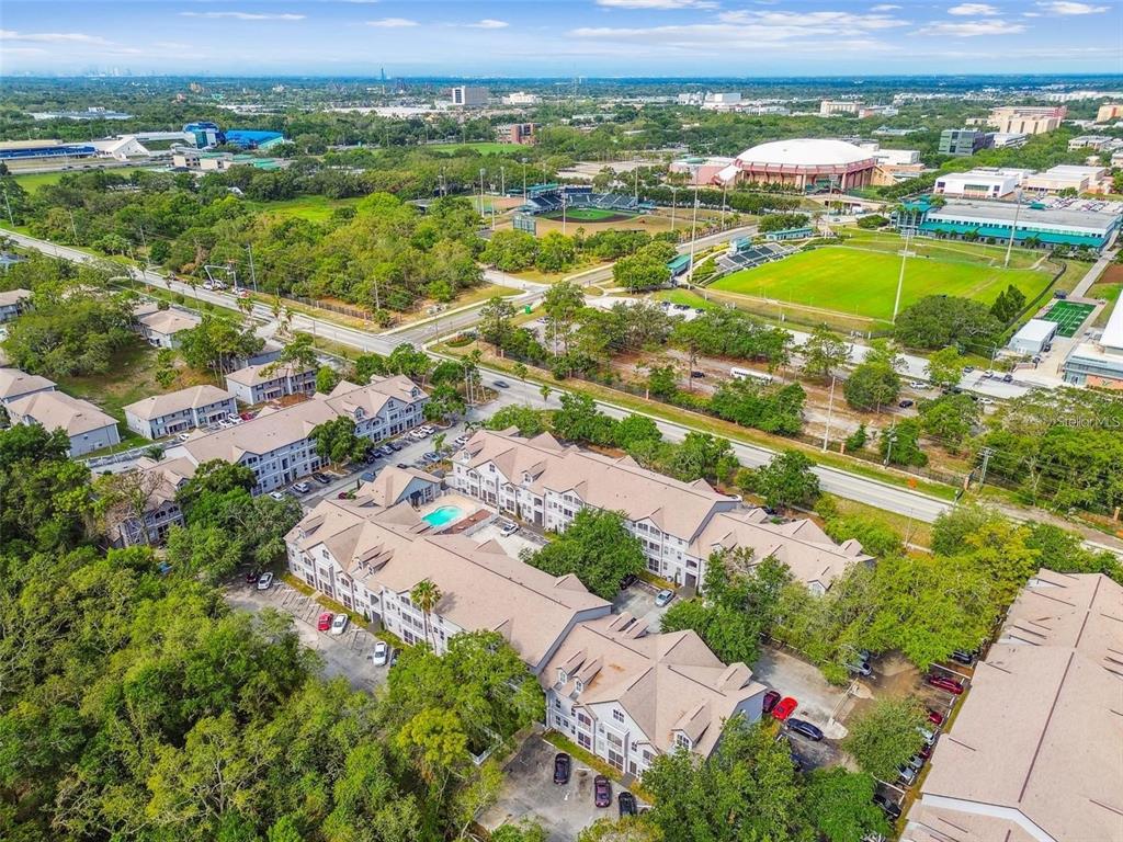 An aerial view shows a multi-story apartment complex with a pool and nearby sports fields — 5154 SUNRIDGE PALMS DRIVE UNIT 5154, TAMPA, FL