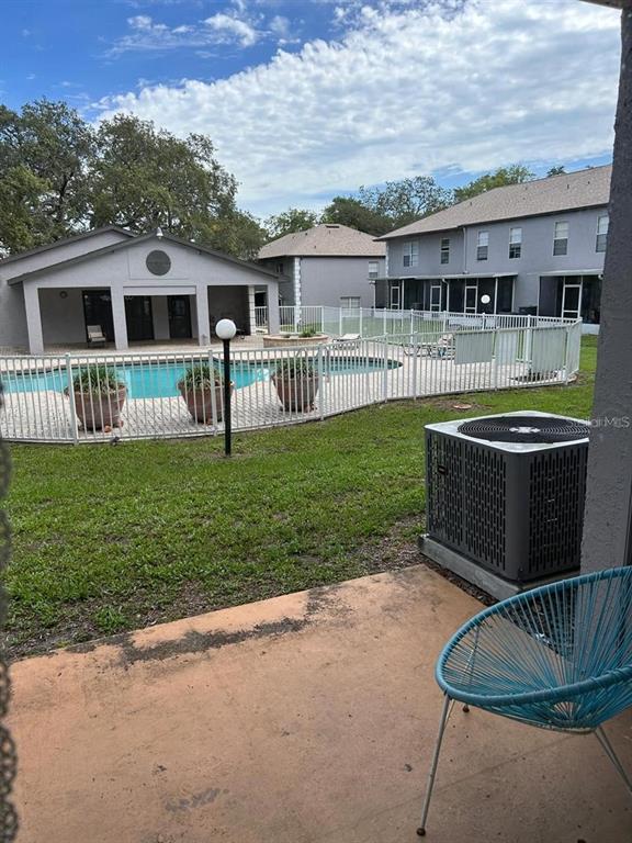 A patio with a blue chair overlooks a swimming pool and a multi-story apartment building — 5154 SUNRIDGE PALMS DRIVE UNIT 5154, TAMPA, FL