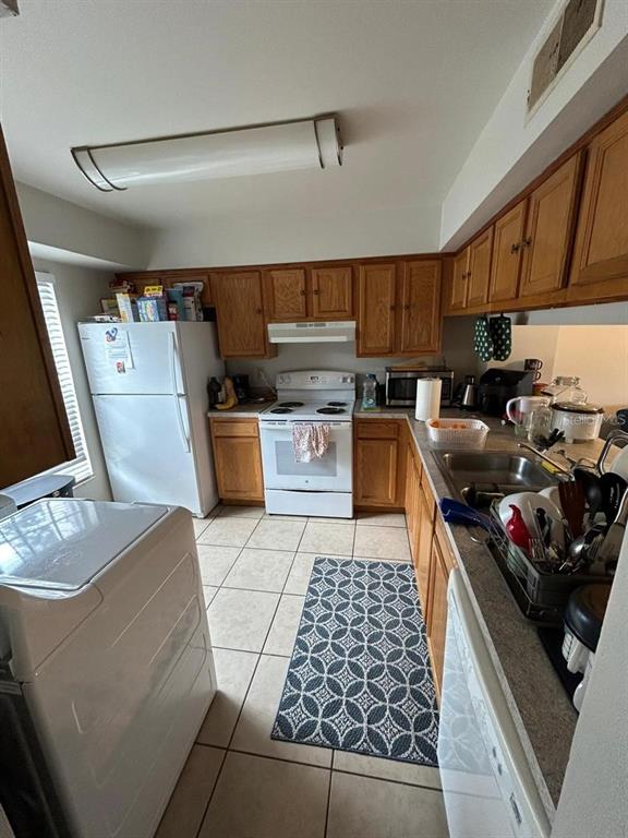 A kitchen features wood cabinets, white appliances, tile flooring, and a patterned area rug — 5154 SUNRIDGE PALMS DRIVE UNIT 5154, TAMPA, FL