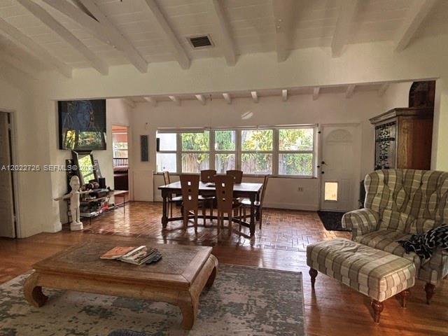 A living room with a wooden coffee table, dining set, and vaulted beamed ceiling — 8228 NE 8th Ct, Miami FL 33138, MIAMI, FL