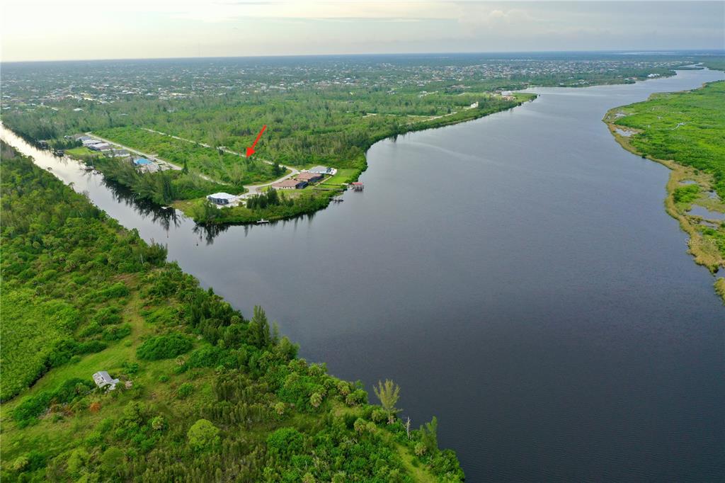 An aerial view shows a waterfront lot with a red arrow pointing toward vegetation — 16449 LIGGETT CIRCLE, PORT CHARLOTTE, FL